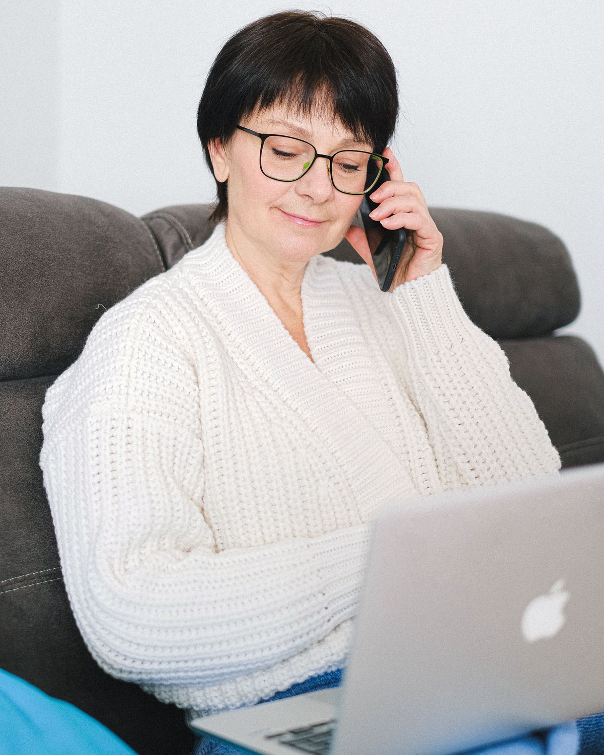 Smiling woman on a phone call at home with her laptop
