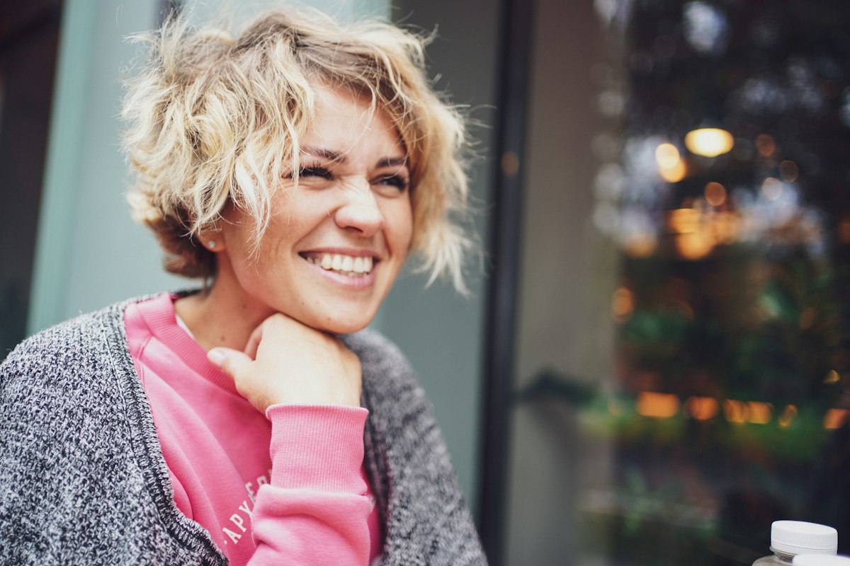 Smiling woman in a pink shirt and gray cardigan