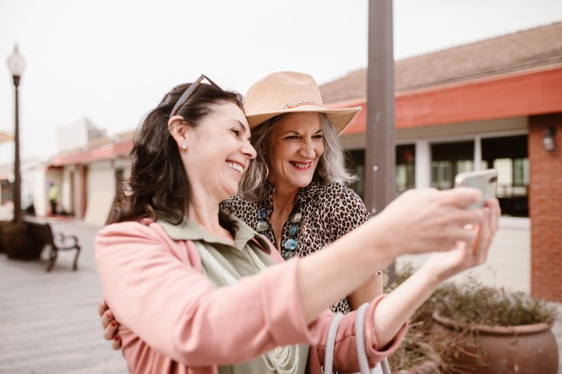 Two women smiling while taking a selfie outdoors