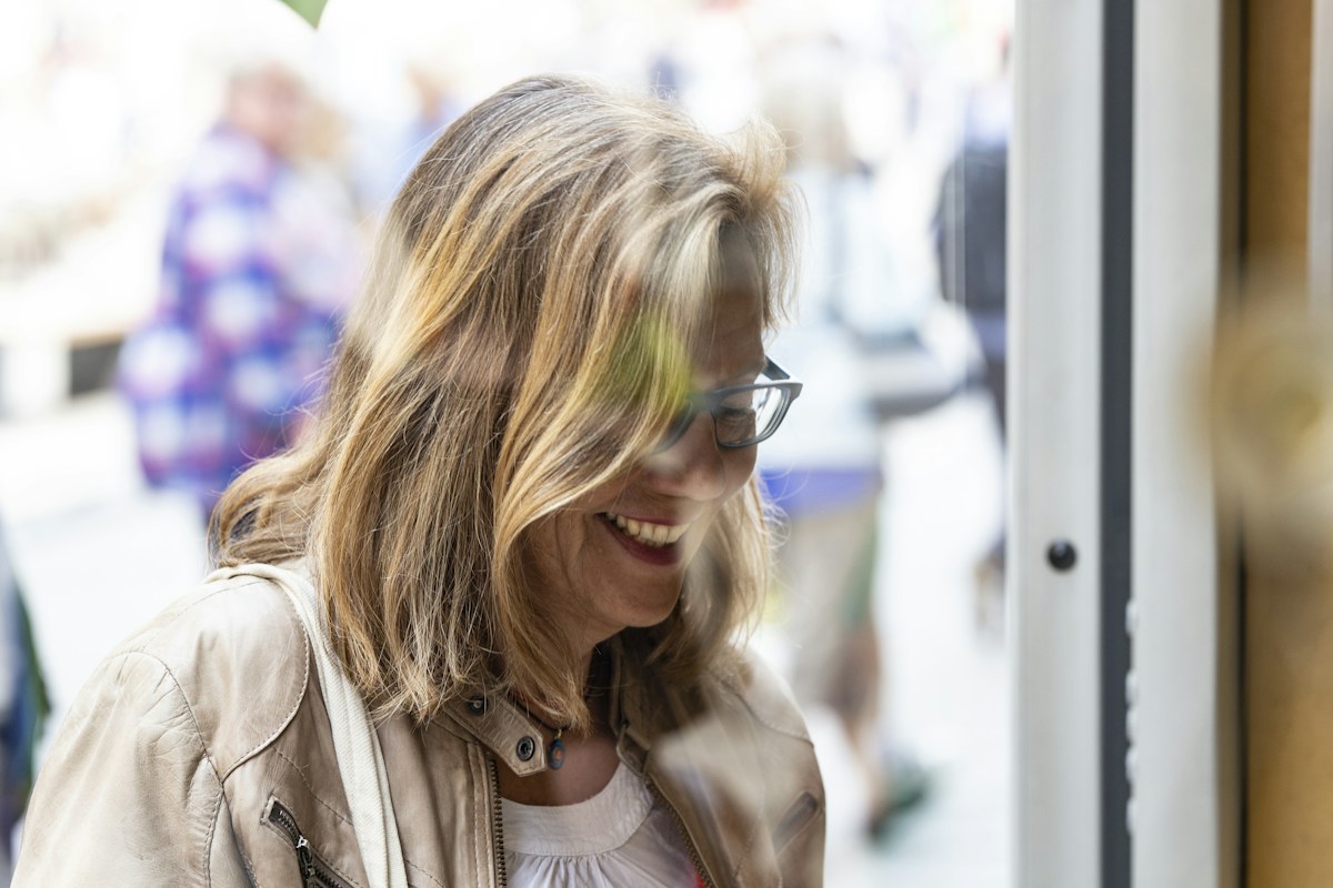 Woman in glasses smiling beside a bright window