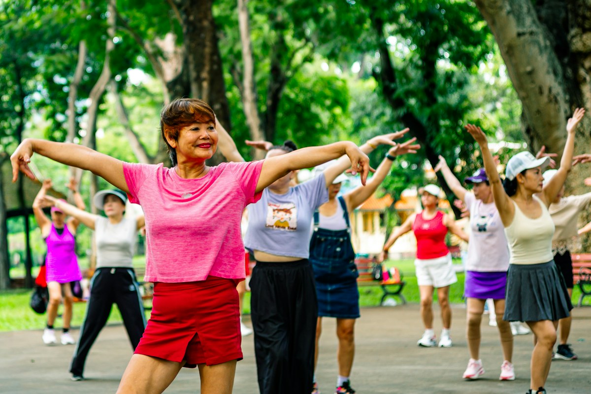 Women stretching their arms together in a green park