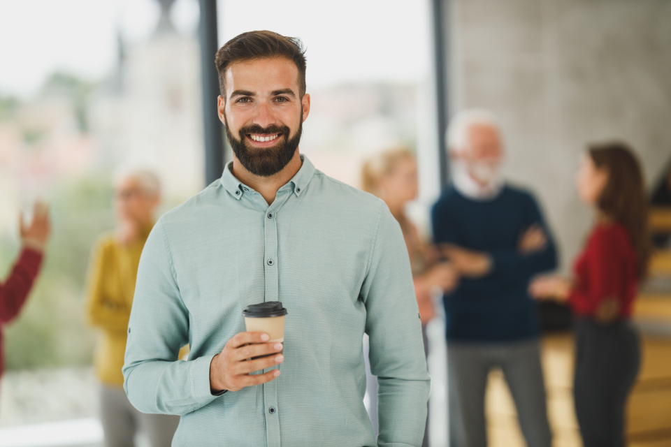 Smiling bearded man holding a coffee cup indoors