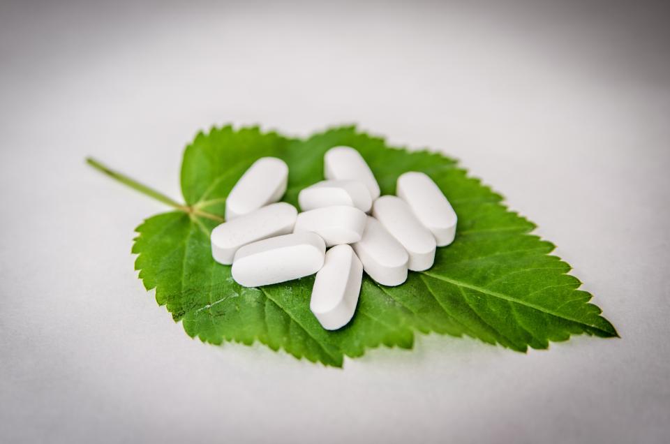 White compounded tablets resting on a fresh green leaf