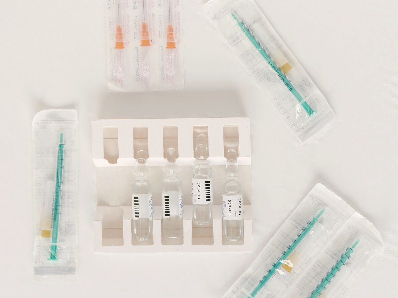 Sterile syringes and single-dose medication ampoules laid out on a clean surface