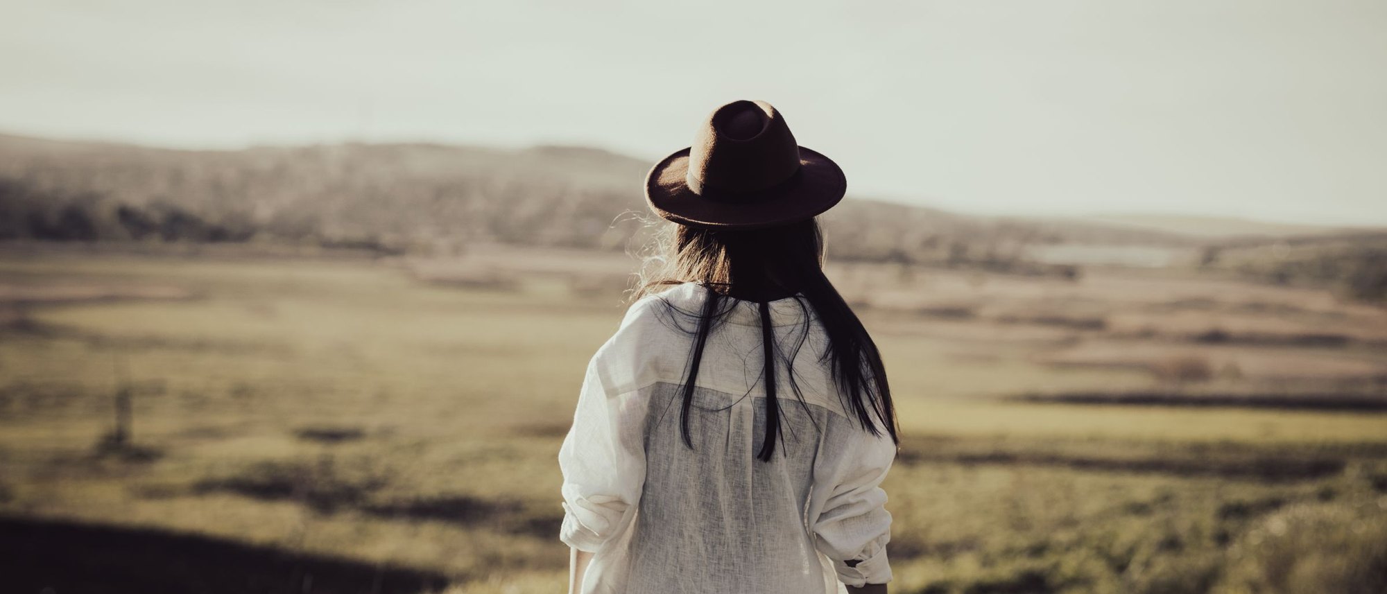 Woman looking out over open countryside in warm light